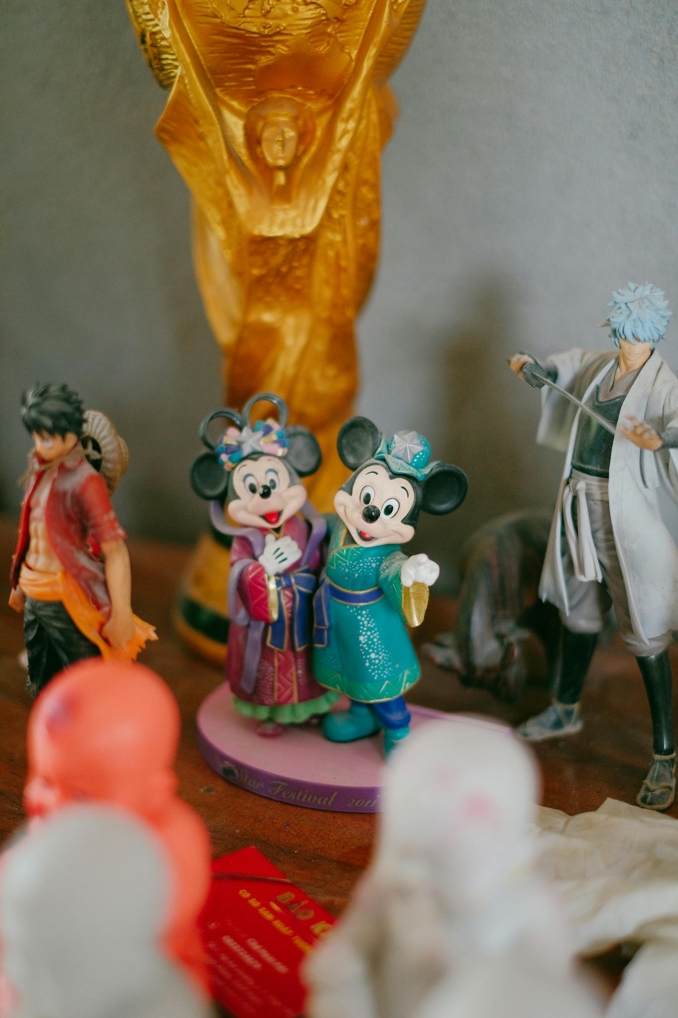 Close-up of assorted figurines including Mickey and Minnie with a golden trophy in the background.